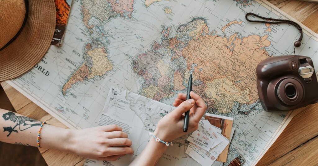 Map_travelling_plan Top view of a woman's hands planning a trip with a map, camera, and travel items.